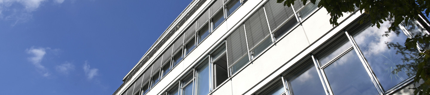 Fensterfront des Geschossbaus mit blauem Himmel